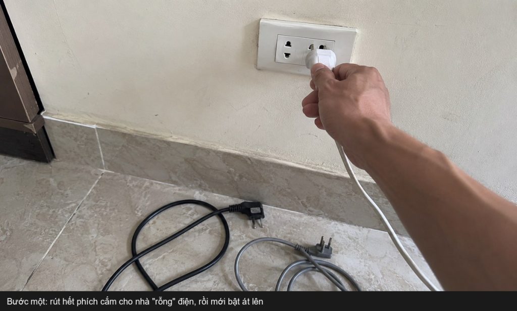 Bàn tay rút phích cắm khỏi ổ điện tường